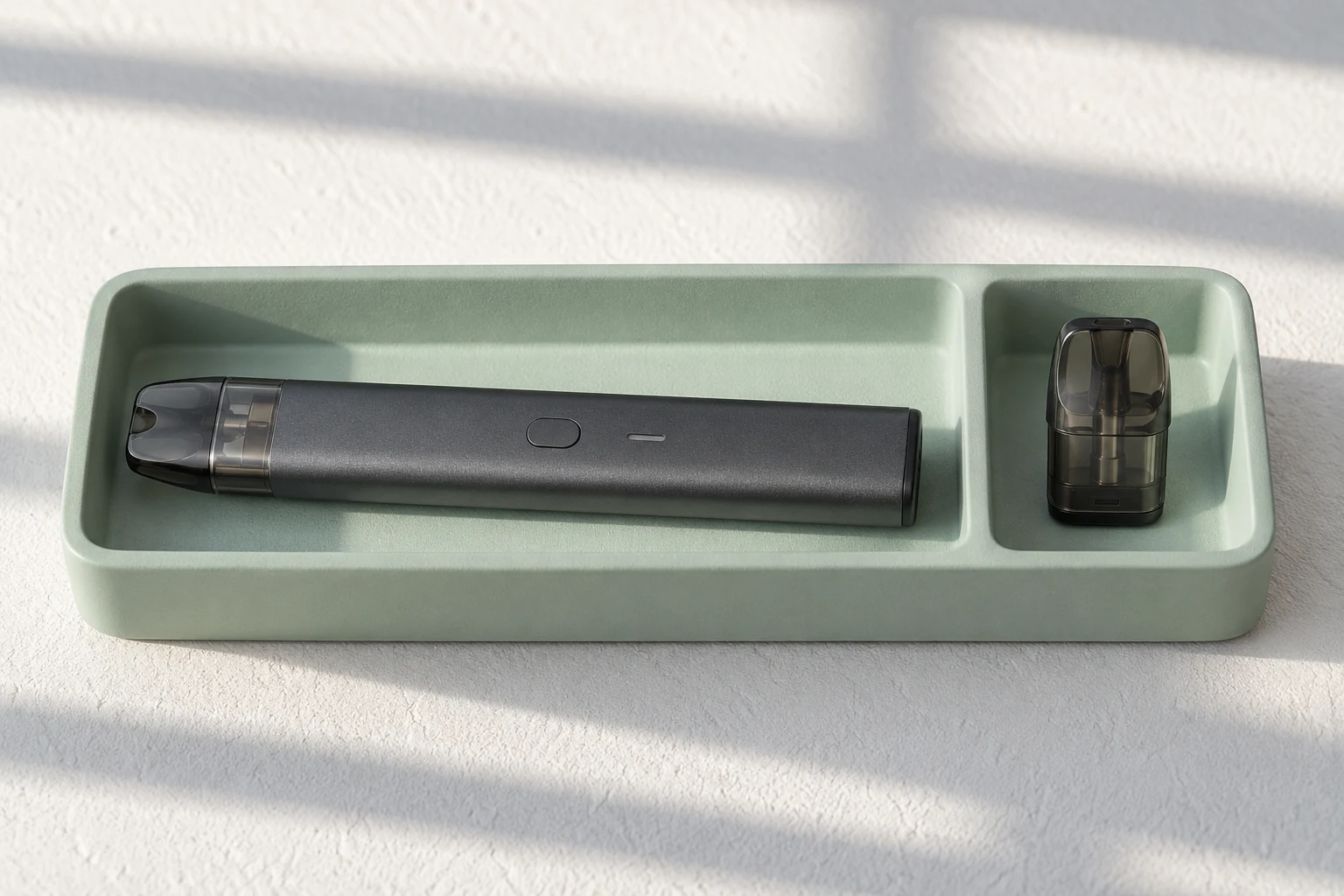 Geschlossenes symbolisches Basisgerät und separater Pod liegen in zwei Fächern einer mintgrünen Ablage.